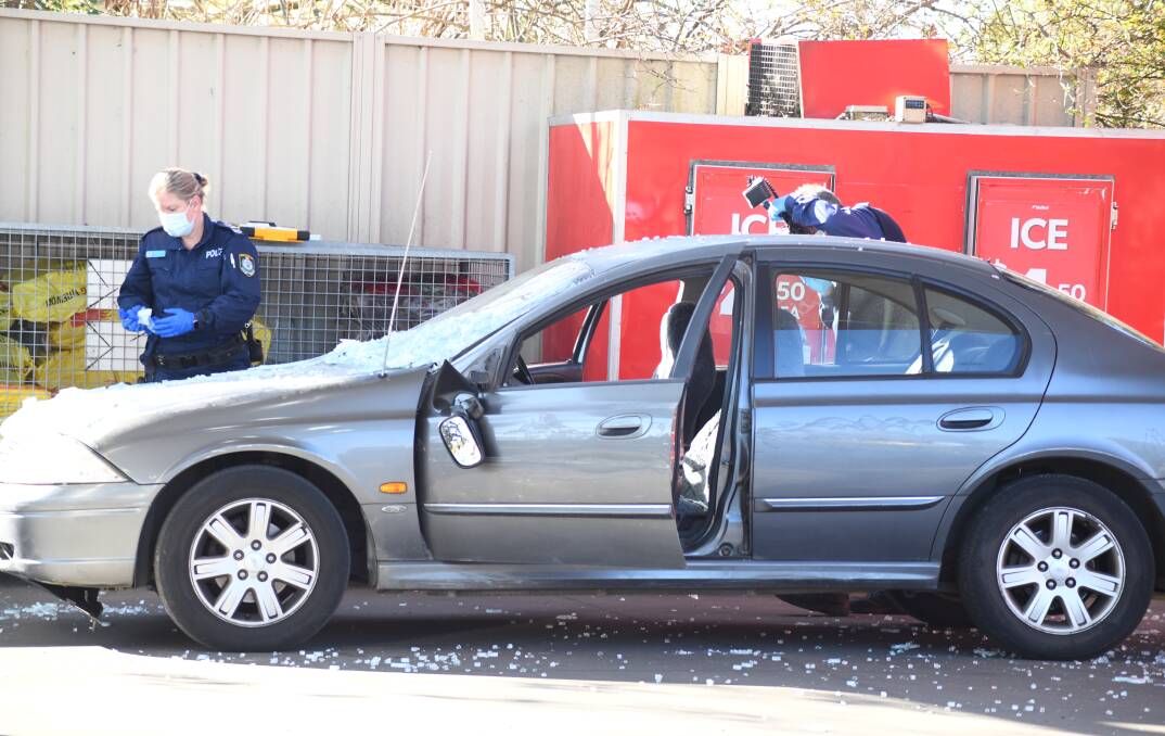 Forensics inspect a grey Ford Falcon that was involved in the September 6 ram and raid at United Petroleum Orange, covered in broken glass. Picture by Jude Keogh.